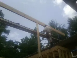 Carpenter setting a ridge beam over a new addition frame — Ice Dam Removal by Roofing Brothers in Calhoun City