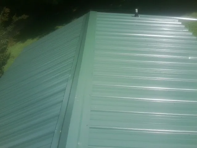 New green metal panels meeting at the ridge of a roof — Flat Roof Repair work by our crew in Calhoun City