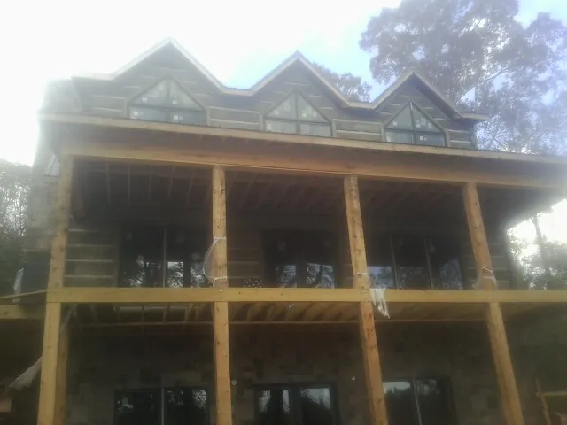 Dormers and porch framing on a large log home under construction — Roof Coating work by our crew in Calhoun City