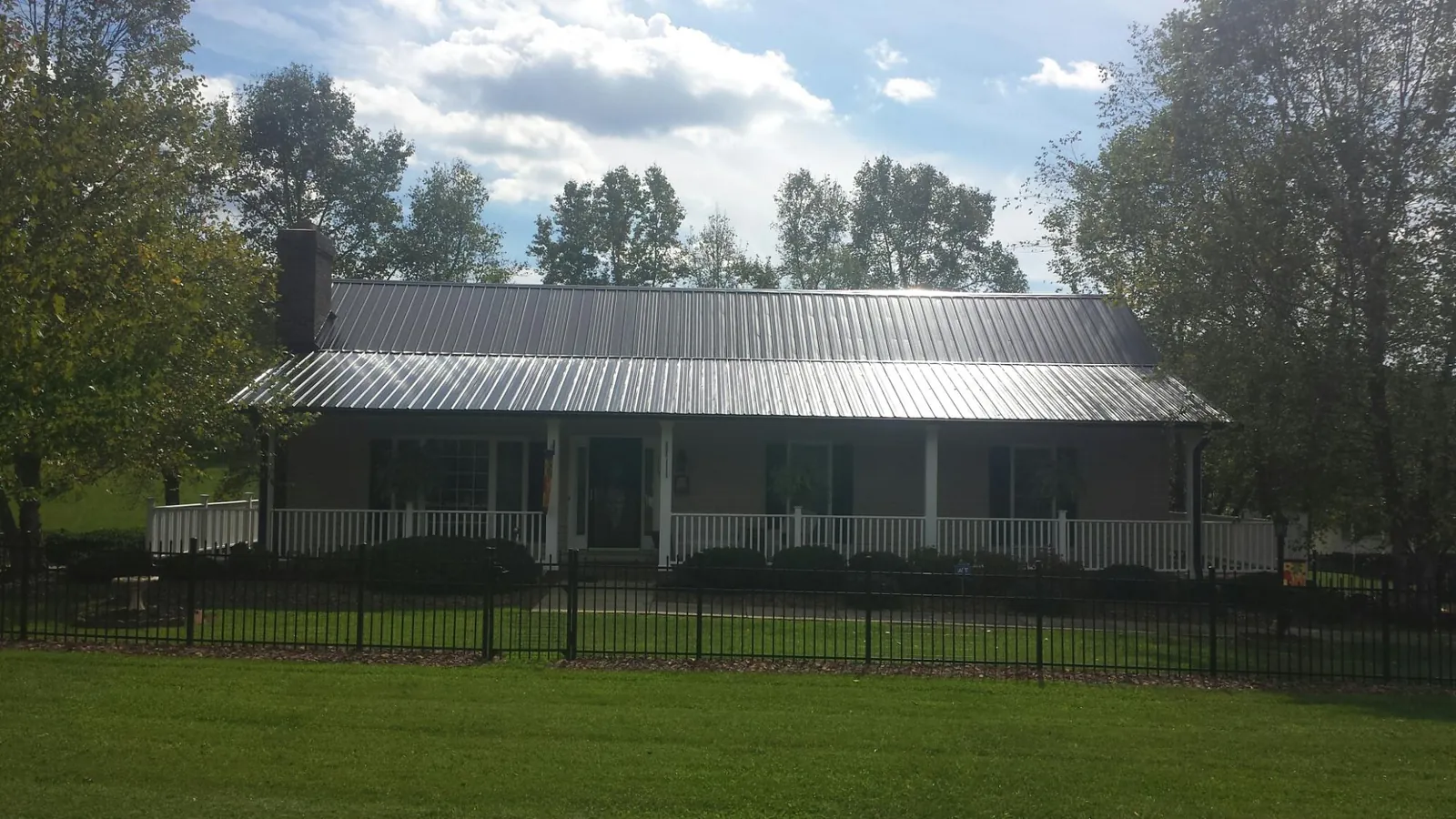 Gray metal roof on a brick ranch with a full width front porch — Gutter Guard Installation work by our crew in Calhoun City