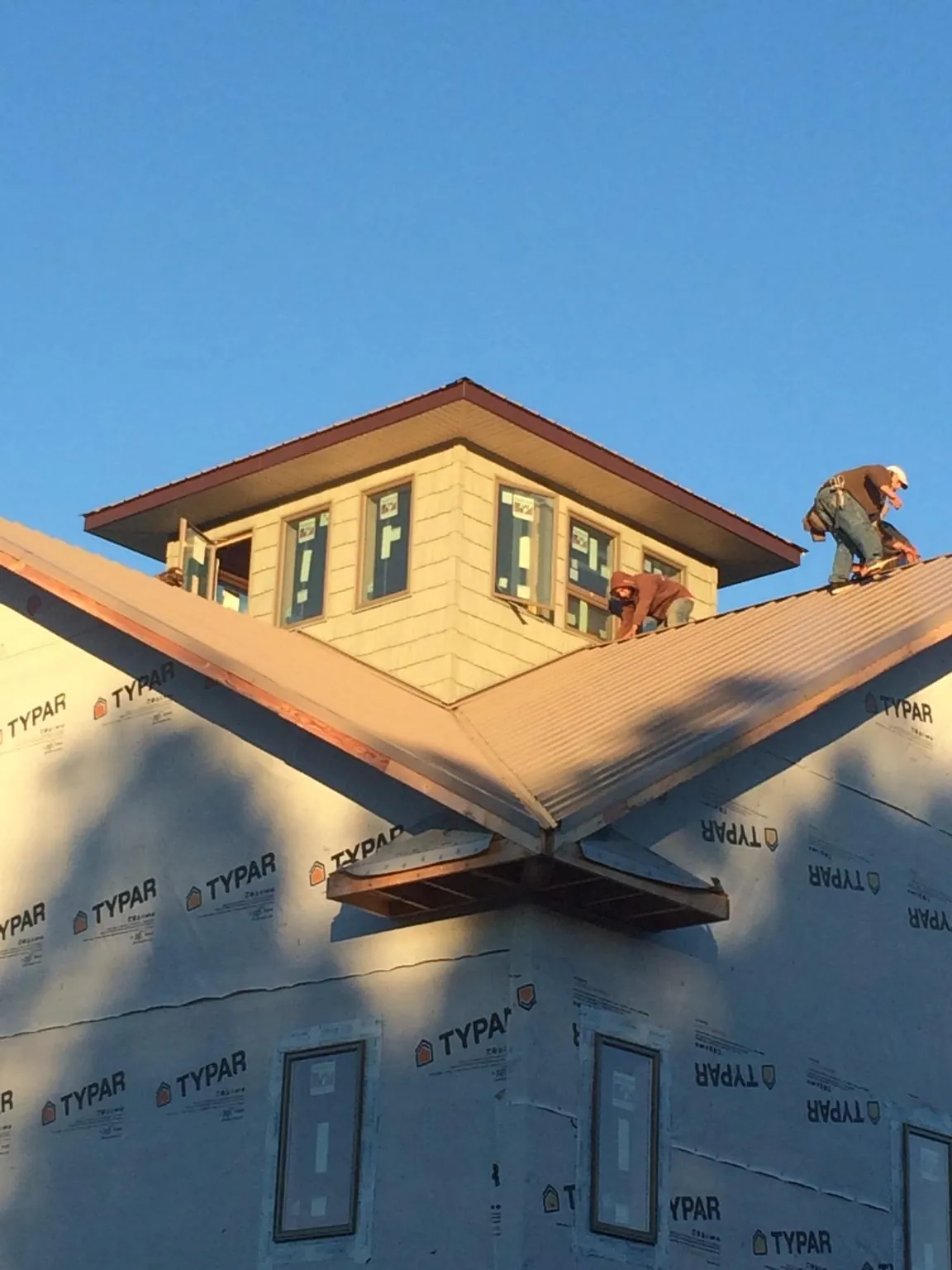 Roofers working around a rooftop cupola on a new metal roof at sunset — Roof Waterproofing in Calhoun City by Roofing Brothers